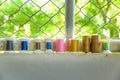 Colourful used thread spools on wall with green background