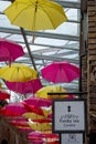 Colourful yellow and red umbrellas hanging above an alleyway full of boutique stores in Camden Market, north London, UK