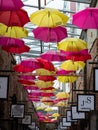 Colourful yellow and red umbrellas hanging above an alleyway full of boutique stores in Camden Market, north London, UK