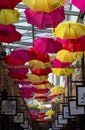 Colourful yellow and red umbrellas hanging above an alleyway full of boutique stores in Camden Market, north London, UK