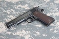 Colt 1911 handgun on camouflage uniform