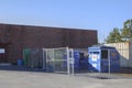 Blue ORION Trash waste dumpsters on the side of a building with fence