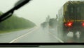 Column of modern military vehicles on the highway. Defocussed traffic viewed through a car windscreen covered in rain This is in