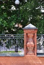 Column of a red brick fence. Forged metal fence.