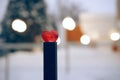 A column with a red heart at the end. In the background are lights in outfocus, bokeh. Winter background