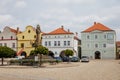 Column with sculptural group of Holy Trinity, sunny day, renaissance and baroque historical buildings, arcade, colorful houses,