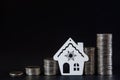 Columns of coins and the contour of the house on a black background. The concept of savings, the concept of profit growth and real