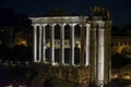 columns of the Temple of Saturn on the Palatine Hill illuminated at night with white light in the city of Rome.