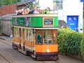 COLYTON, DEVON, ENGLAND - AUGUST 6TH 2012: An orange and green tram pulls into Colyford station on the Seaton tramway. Passengers