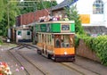 COLYTON, DEVON, ENGLAND - AUGUST 6TH 2012: An orange and green tram pulls into Colyford station on the Seaton tramway. Passengers