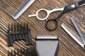 Comb, scissors, razor and hair clipper lie on a brown wooden table