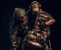 Combat conflict, special mission, retreat. Military medic rescues his wounded teammate carrying him off the battlefield. Royalty Free Stock Photo