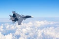Combat fighter jet flies turning maneuver high in the sky above the clouds