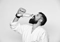 Combat master drinks refreshing water after training. Man with beard in kimono on white background. Workout and