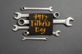 Combination wrenches, card with phrase happy father`s day on grey background. Minimal style and holiday concept.