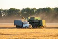 A combine dumps soybeans into a semi tractor-trailer at sundown Royalty Free Stock Photo