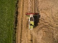 Combine harvester - Aerial view of modern combine harvester at the harvesting the wheat on the golden wheat field in the summer Royalty Free Stock Photo