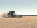 A combine harvester drives away from the camera on a wa grain farm