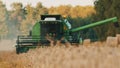 Combine Harvester with a farmer sitting can be seen through the dust cloud - Ripe wheat ears