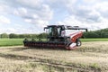 Combine harvester in a field against a background of blue sky and green grass. Working Harvesting Combines in the Field.