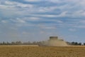 Combine harvester harvests ripe wheat. Ripe ears of gold field on the cloudy sky background. . Concept of a rich harvest. Royalty Free Stock Photo