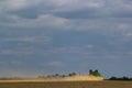 Combine harvester harvests ripe wheat. Ripe ears of gold field on the cloudy sky background. . Concept of a rich harvest. Royalty Free Stock Photo