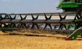 Combine harvester harvests ripe wheat. Ripe ears of gold field on the cloudy sky background. . Concept of a rich harvest. Royalty Free Stock Photo