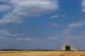 Combine harvester harvests ripe wheat. Ripe ears of gold field on the cloudy sky background. . Concept of a rich harvest. Royalty Free Stock Photo