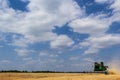 Combine harvester harvests ripe wheat. Ripe ears of gold field on the cloudy sky background. . Concept of a rich harvest. Royalty Free Stock Photo