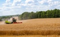 Combine harvester harvests ripe wheat in field Royalty Free Stock Photo