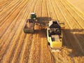 Combine harvester load wheat seed to the trailer. Aerial view. Royalty Free Stock Photo