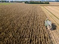 Combine harvester picking seed from fields, aerial view of a field with a combine harvester with cornhusker gathering the crop