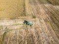 Combine harvester picking seed from fields, aerial view of a field with a combine harvester with cornhusker gathering the crop