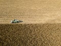 Combine harvester picking seed from fields, aerial view of a field with a combine harvester with cornhusker gathering the crop