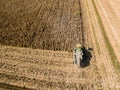 Combine harvester picking seed from fields, aerial view of a field with a combine harvester with cornhusker gathering the crop