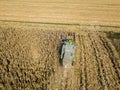 Combine harvester picking seed from fields, aerial view of a field with a combine harvester with cornhusker gathering the crop