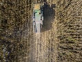 Combine harvester picking seed from fields, aerial view of a field with a combine harvester with cornhusker gathering the crop