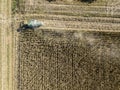 Combine harvester picking seed from fields, aerial view of a field with a combine harvester with cornhusker gathering the crop