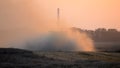 Combine harvester reaping wheat on field in the summer evening. Dust field