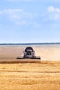 Combine harvester at work in an agricultural field on harvesting wheat, horizontal image, centered Royalty Free Stock Photo