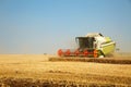 Combine harvester working on a golden ripe wheat field on a bright summer day against blue sky. Grain dust in the air. Agricultura Royalty Free Stock Photo