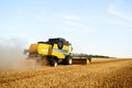 Combine harvester working in wheat field with clear blue sky. Harvesting machine driver cutting crop in a farmland Royalty Free Stock Photo