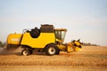 Combine harvester working in wheat field with clear blue sky. Harvesting machine driver cutting crop in a farmland Royalty Free Stock Photo