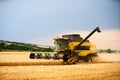 Combine harvester working in wheat field with cloudy moody sky. Harvesting machine driver cutting crop in a farmland Royalty Free Stock Photo