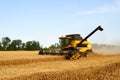 Combine harvester working in wheat field with clear blue sky. Harvesting machine driver cutting crop in a farmland Royalty Free Stock Photo