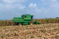 Combine harvesters are working in corn fields. Harvesting of corn field with combine in early autumn. Royalty Free Stock Photo