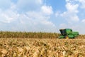Combine harvesters are working in corn fields. Harvesting of corn field with combine in early autumn. Royalty Free Stock Photo