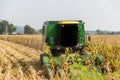 Combine harvesters are working in corn fields. Harvesting of corn field with combine in early autumn. Royalty Free Stock Photo