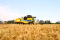 Combine harvesters working in wheat field with clear blue sky. Harvesting machine driver cutting crop in a farmland Royalty Free Stock Photo