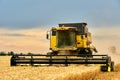 Combine harvesters working in wheat field with cloudy moody sky. Harvesting machine driver cutting crop in a farmland Royalty Free Stock Photo